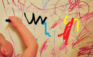 toddler using a marker to write on the wall